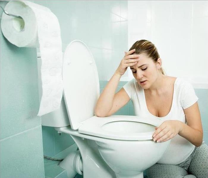 Image of a person holding their head while looking at a toilet